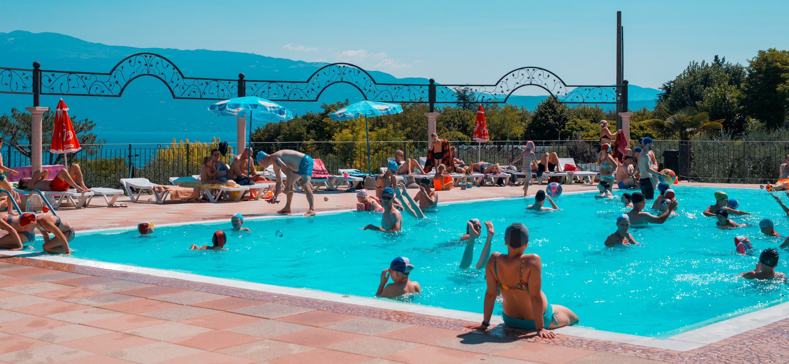 Schwimmbad im Camping Eden mit Sonnenbereich und Blick auf den Gardasee